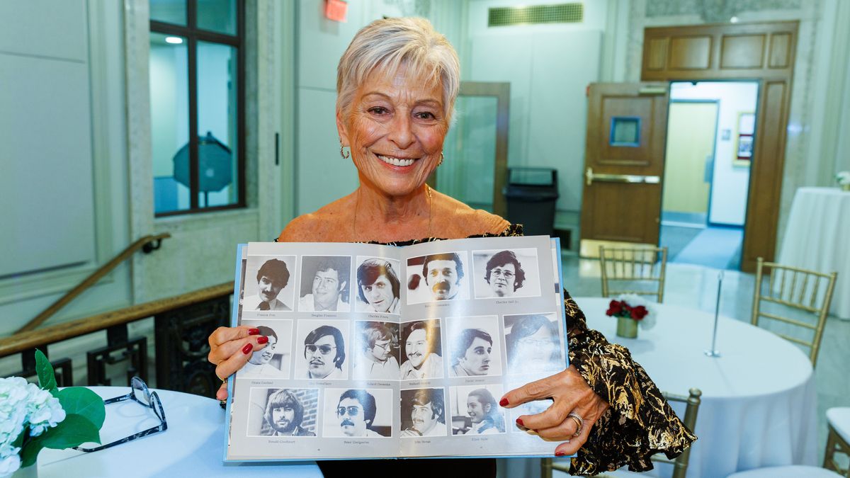 MCPHS Alum holds open a yearbook.