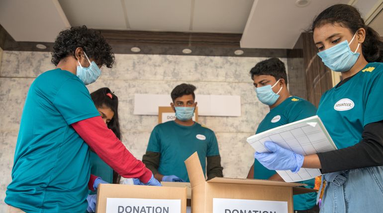 Group of volunteers busy working by arranging clothes and donation boxes 