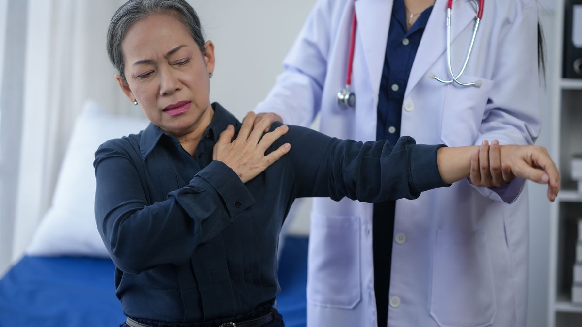 Senior woman experiencing shoulder pain during a medical examination with doctor in a clinic.