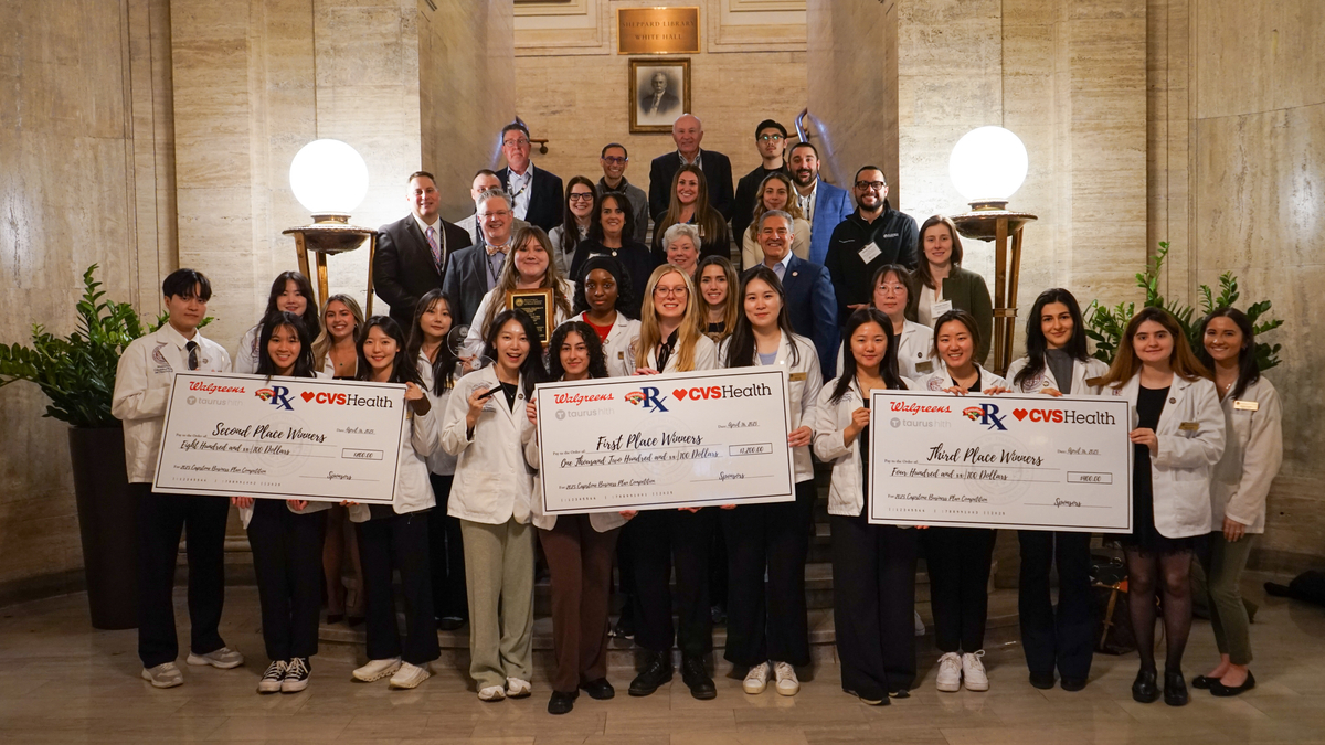 People holding large checks at the MCPHS Annual Capstone Business Plan Competition