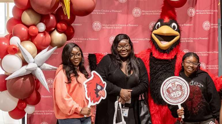 New MCPHS students stand with Red the Cardinal.