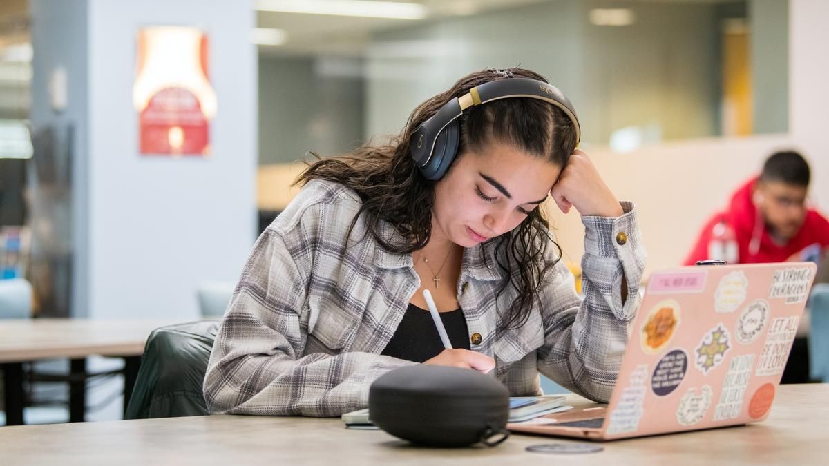 Student wearing headphones and sitting in front of a laptop. 