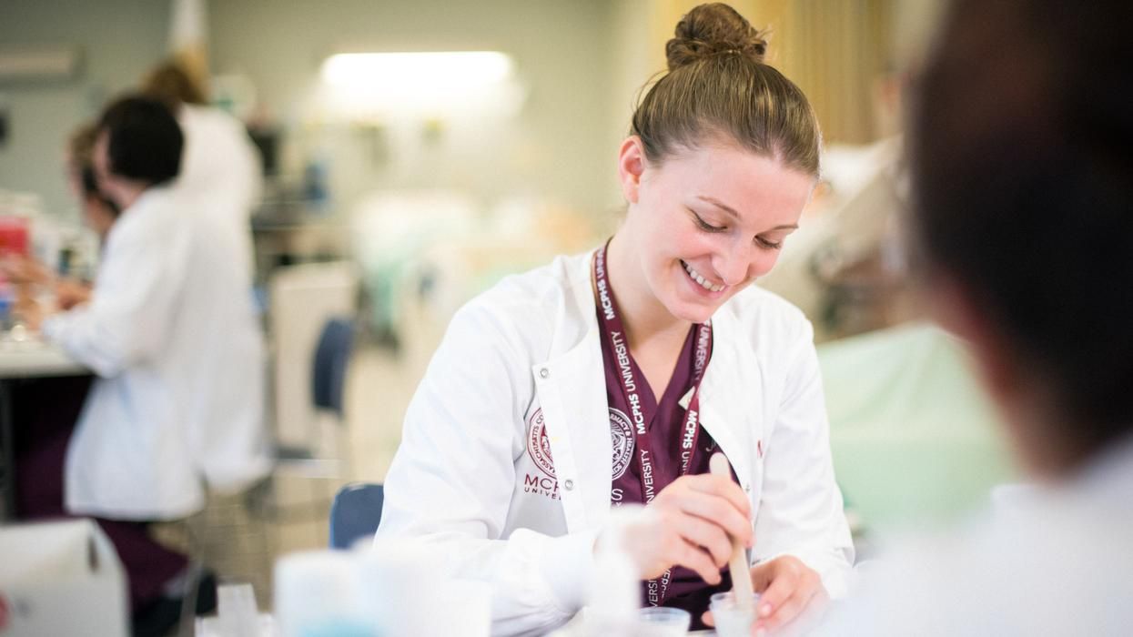 MCPHS female nursing student in the lab mixing medication. 