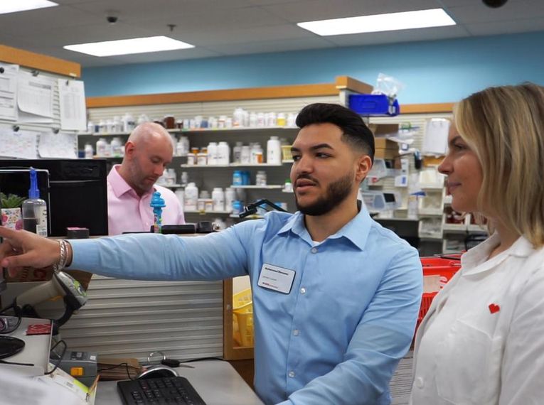 Muhammad Elsweesy looking at a computer in a pharmacy with a woman.