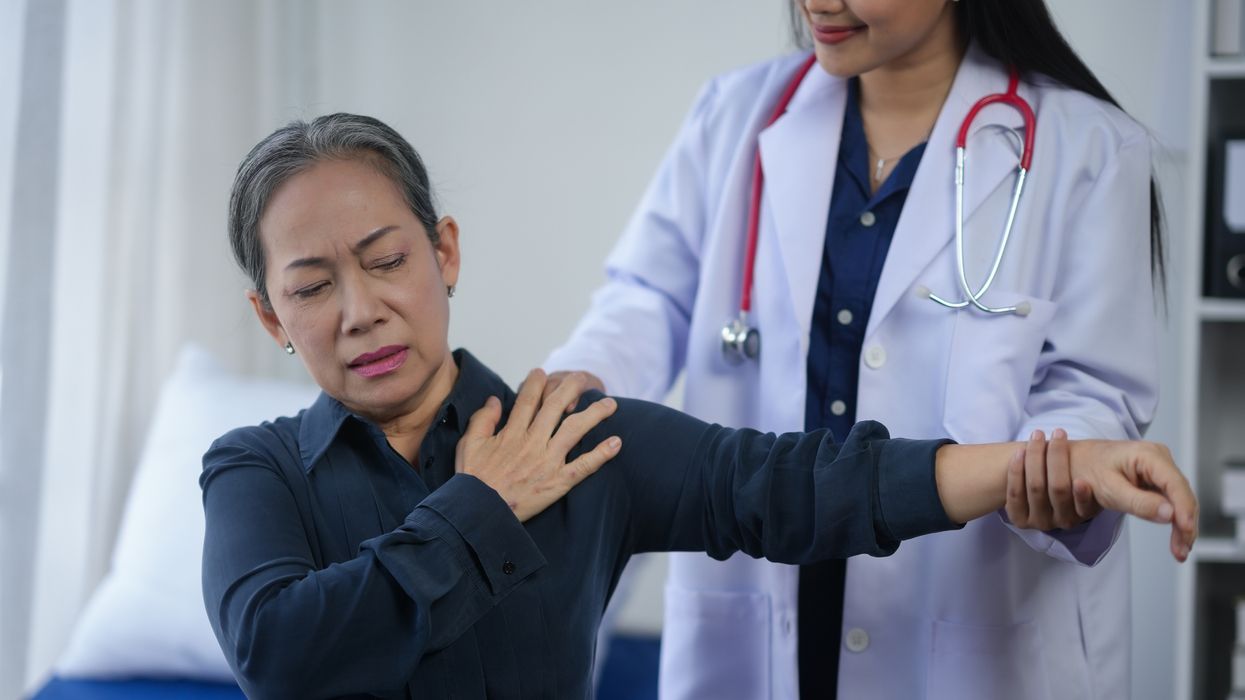 Senior woman experiencing shoulder pain during a medical examination with doctor in a clinic.