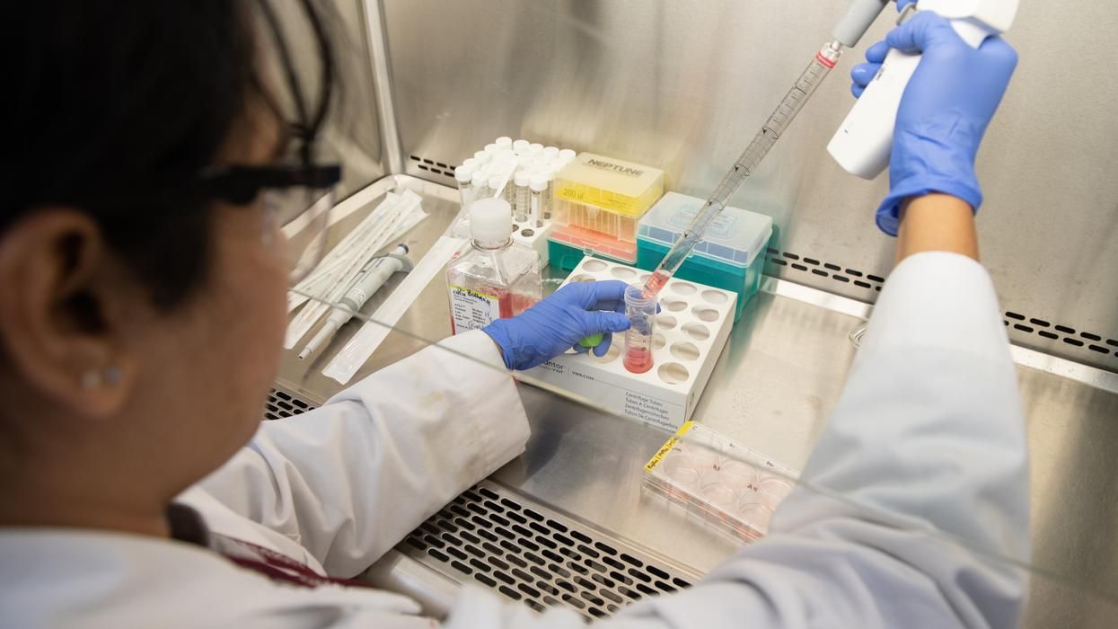 A woman is working in a lab with a pipette.	