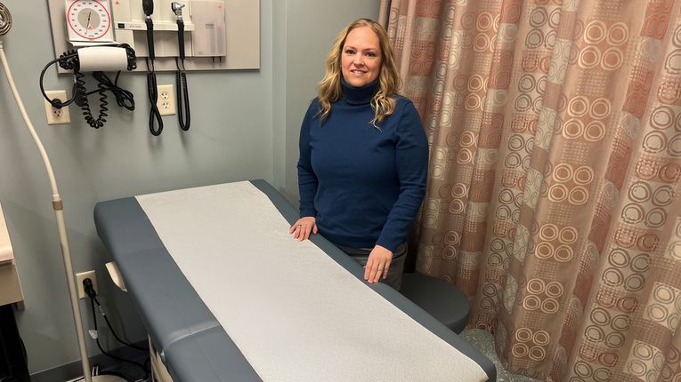 Nicole Dettmann stands beside a gurney in a hospital room.