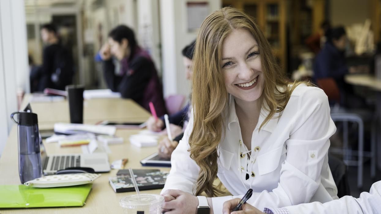 Student smiling at the camera in a library. 