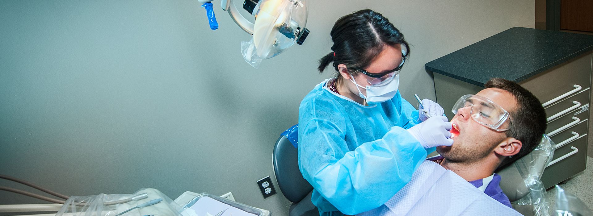 a dental hygiene student working on a patient