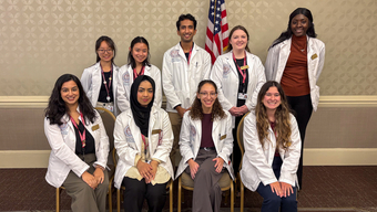 Nine students from Massachusetts College of Pharmacy and Health Sciences (MCPHS) smiling before a presentation on falls awareness.