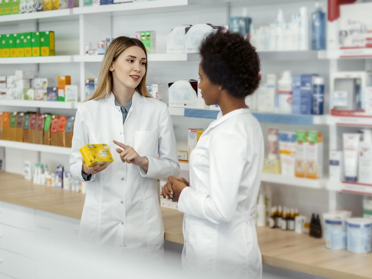 Two female pharmacists talking in a pharmacy.