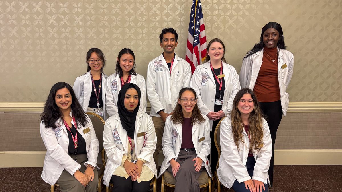 Nine students from Massachusetts College of Pharmacy and Health Sciences (MCPHS) smiling before a presentation on falls awareness.