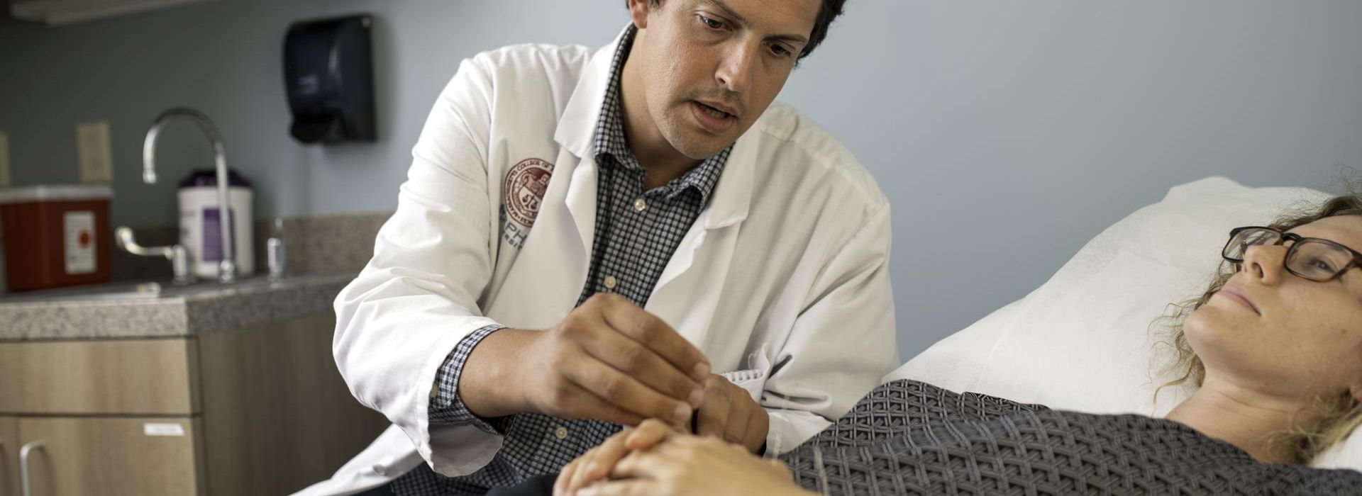 Male Acupuncture student placing a needle into a female patient. 