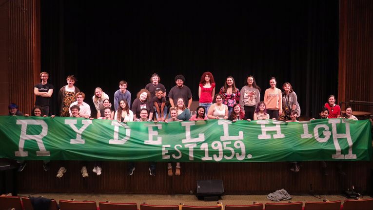 COF Students on stage in front of a Rydell High banner.