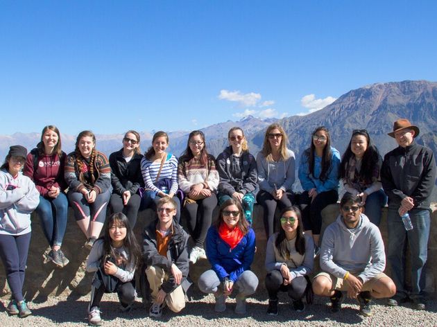 A large group of MCPHS students on a service learning trip to Peru with the mountains in the background