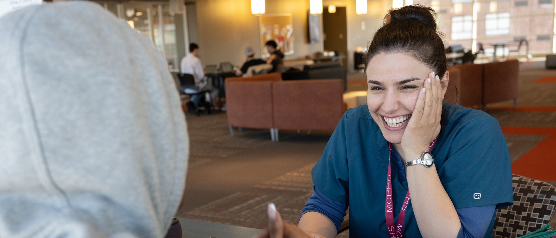 Smiling student wearing scrubs and an MCPHS lanyard.