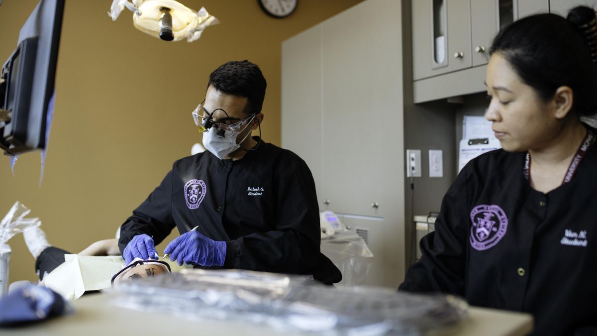 two dentist hygiene students working on a patient in the MCPHS dental clinic..