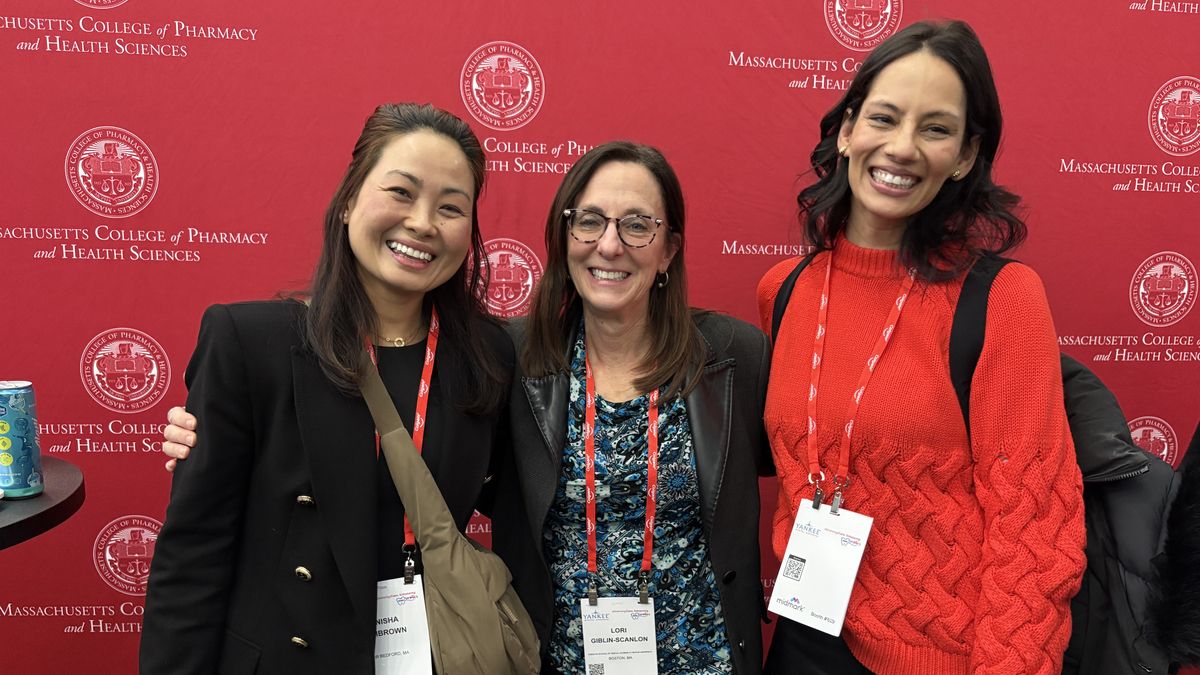 Three women stand in front of an MCPHS backdrop.