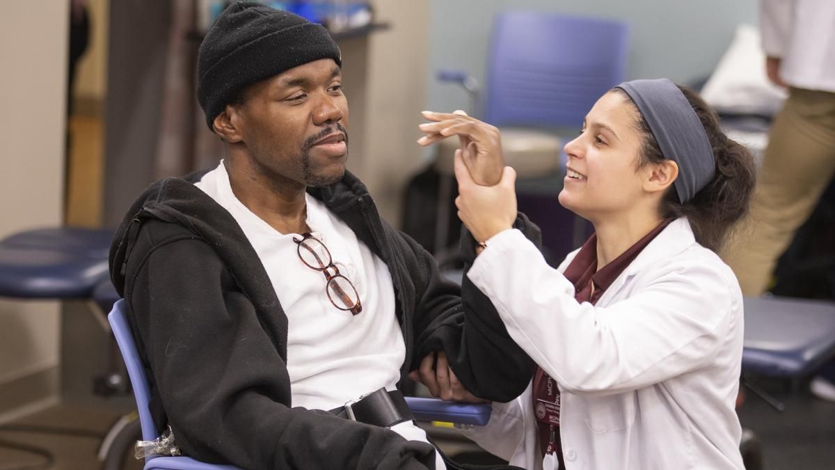 Physical Therapy student holding up a patients hand. 