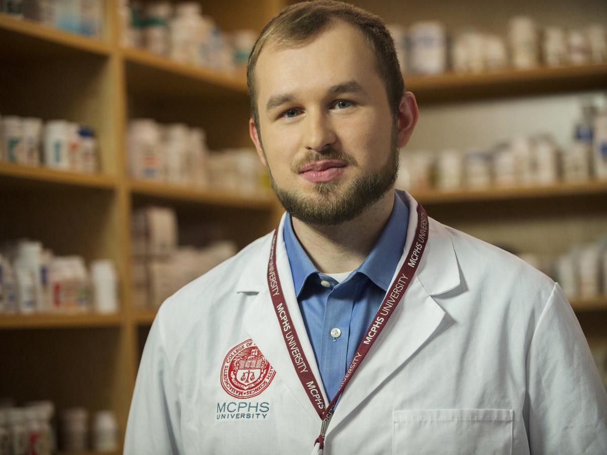 Male student in white lab coat in Pharmacy lab. 