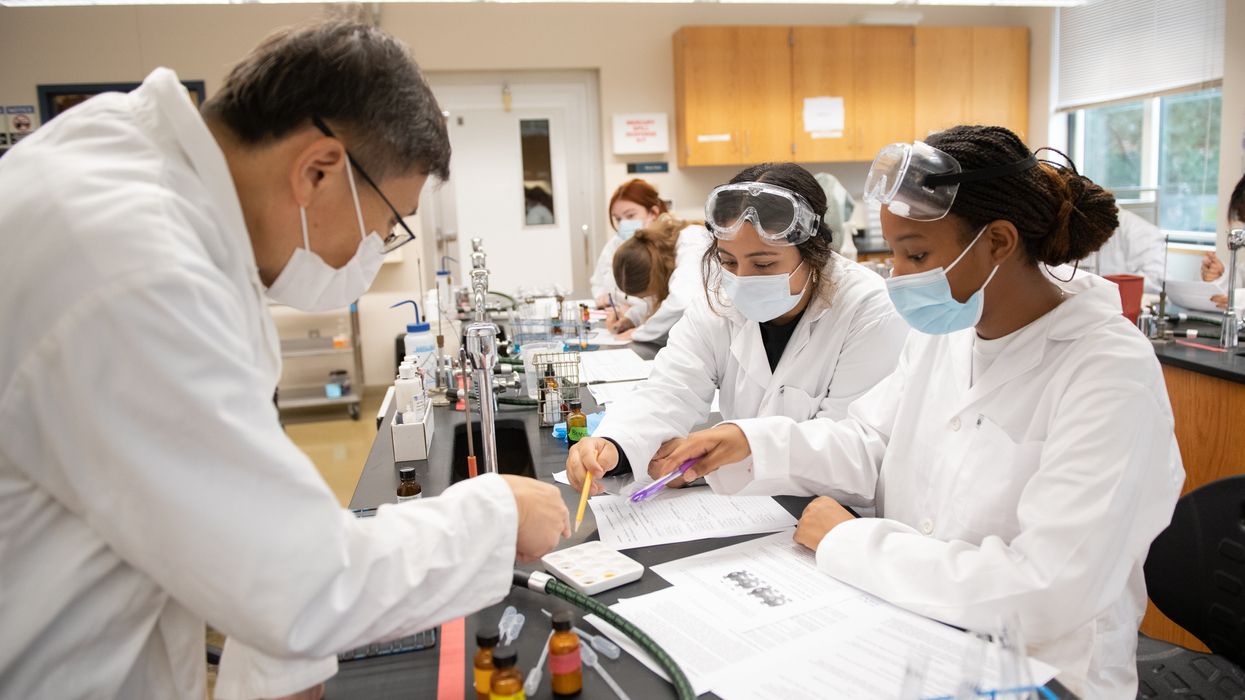 Students in white coats in the chemistry lab. 