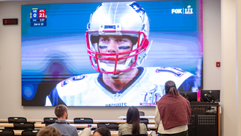 Football player on giant tv screen at MCPHS White 101.