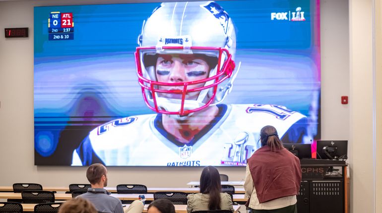 Football player on giant tv screen at MCPHS White 101.