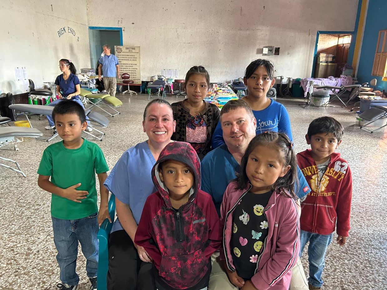 A man and a woman sit with children on a service trip to Guatemala. 