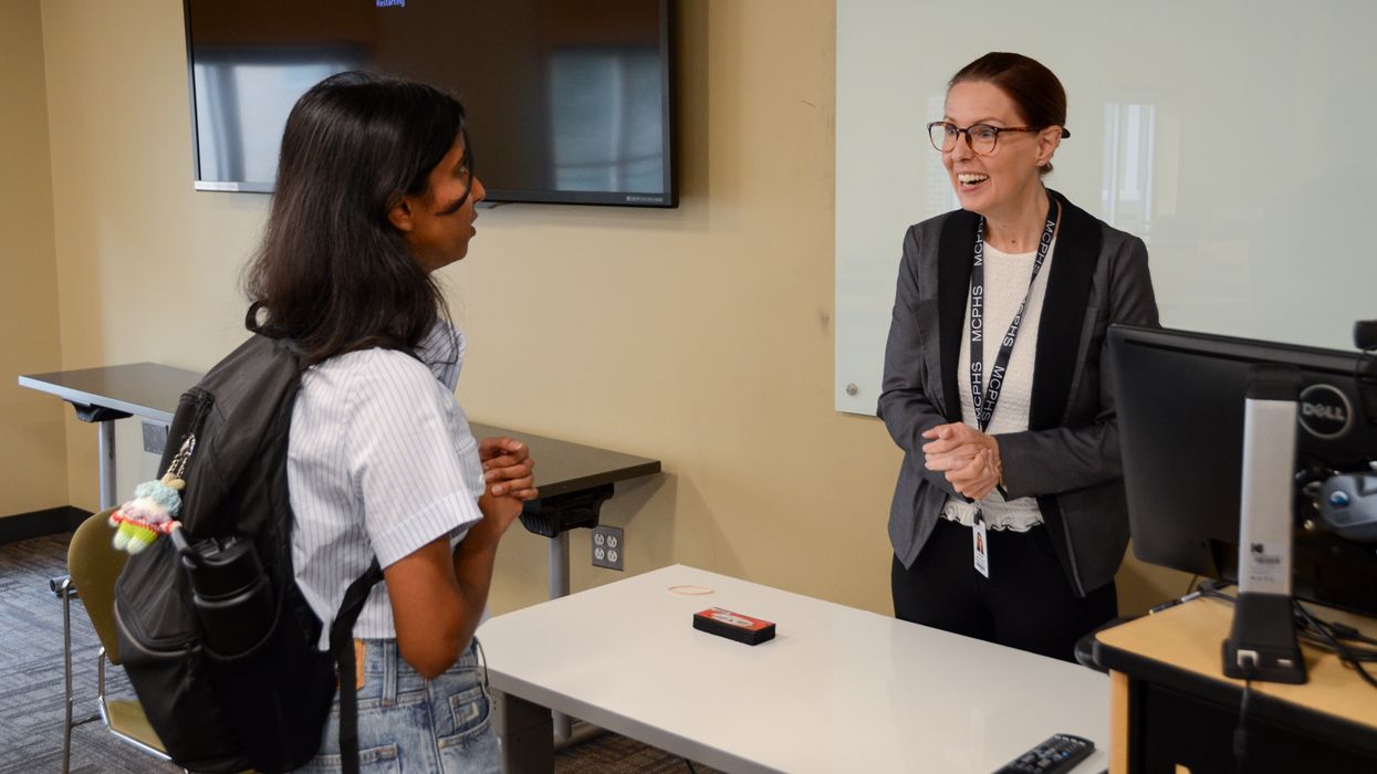 Professor speaks to student in classroom.