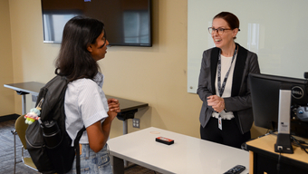 Professor speaks to student in classroom.