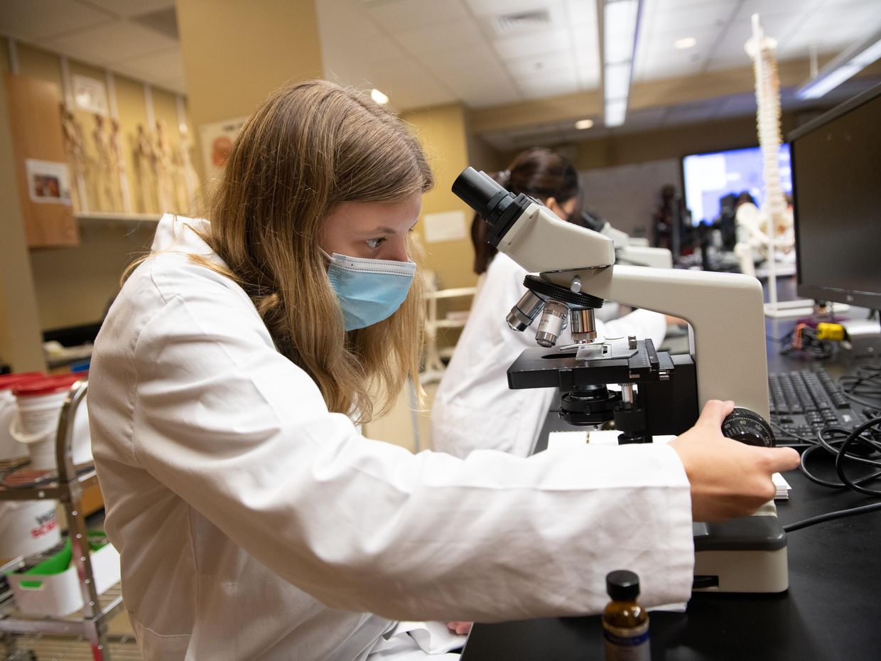 female student looking through a microscope.