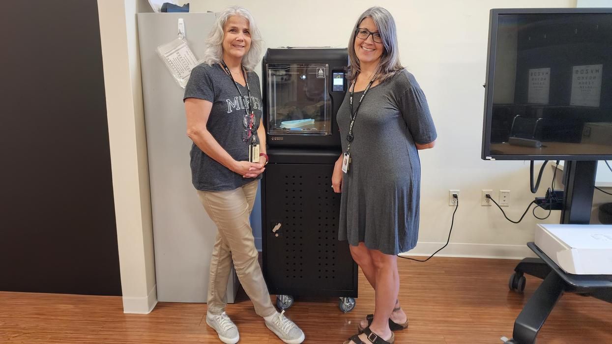 Dr. Michelle Dowling and Dr. Danielle Amero stand in front of a 3D printer.