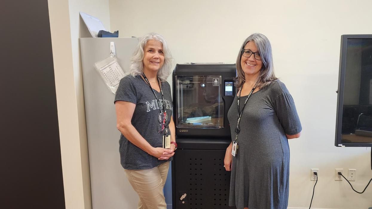 Dr. Michelle Dowling and Dr. Danielle Amero stand in front of a 3D printer.