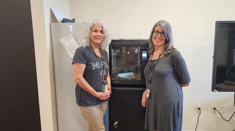 Dr. Michelle Dowling and Dr. Danielle Amero stand in front of a 3D printer.