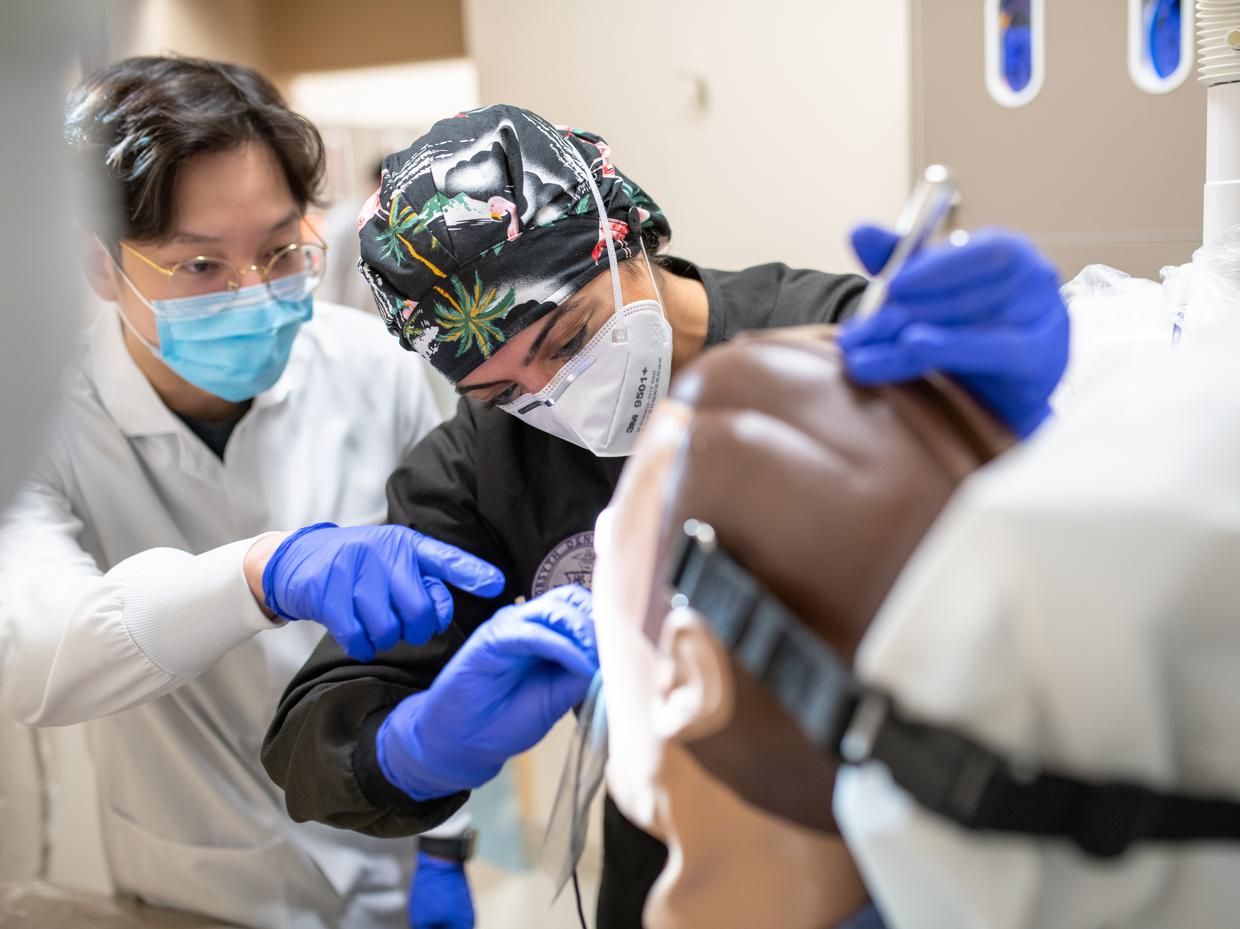 Two dental hygiene students working on manikin.
