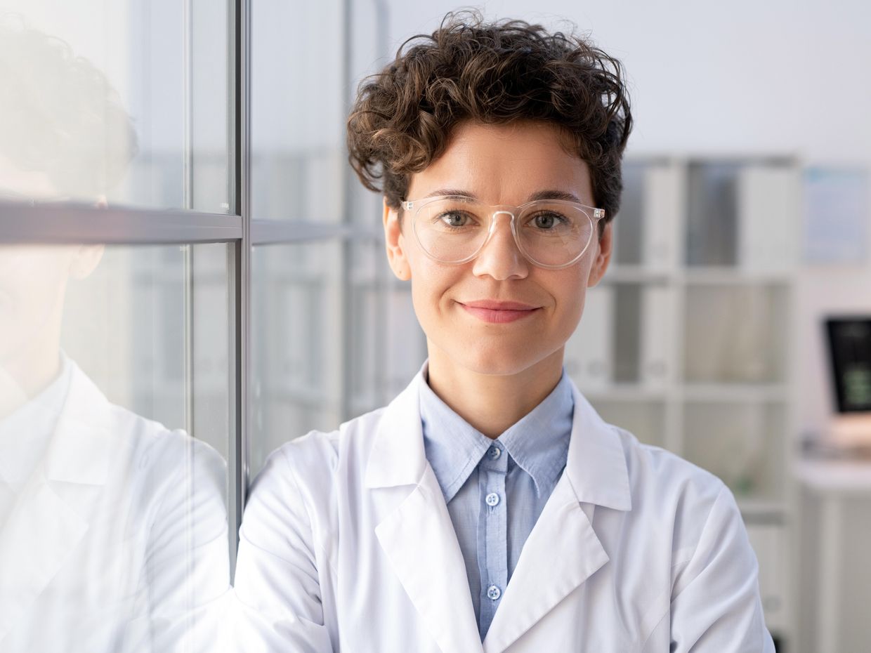 Smiling female in a wearing a white lab coat. 