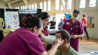 Woman performs an eye exam at MCPHS and Veterans Stand Down Event.