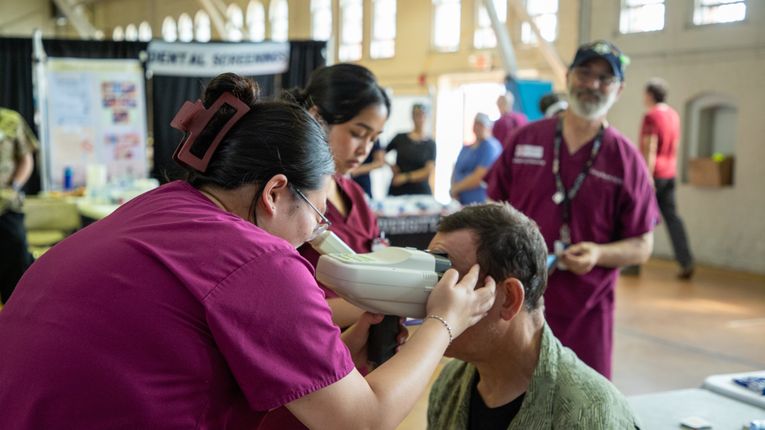 Woman performs an eye exam at MCPHS and Veterans Stand Down Event.