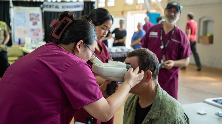 Woman performs an eye exam at MCPHS and Veterans Stand Down Event.