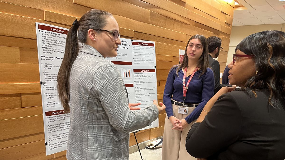 Three women discuss a poster.
