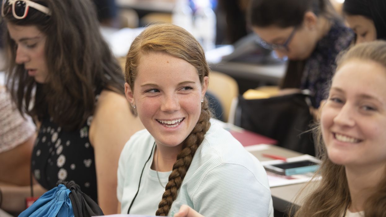 Smiling girl sitting in classroom with other students.