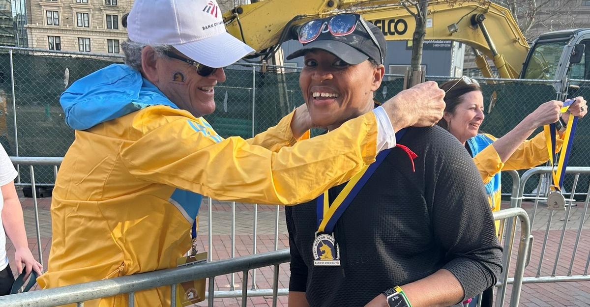 Chrylann Lewis smiles as a volunteer puts a Boston Marathon finisher's medal around her neck.