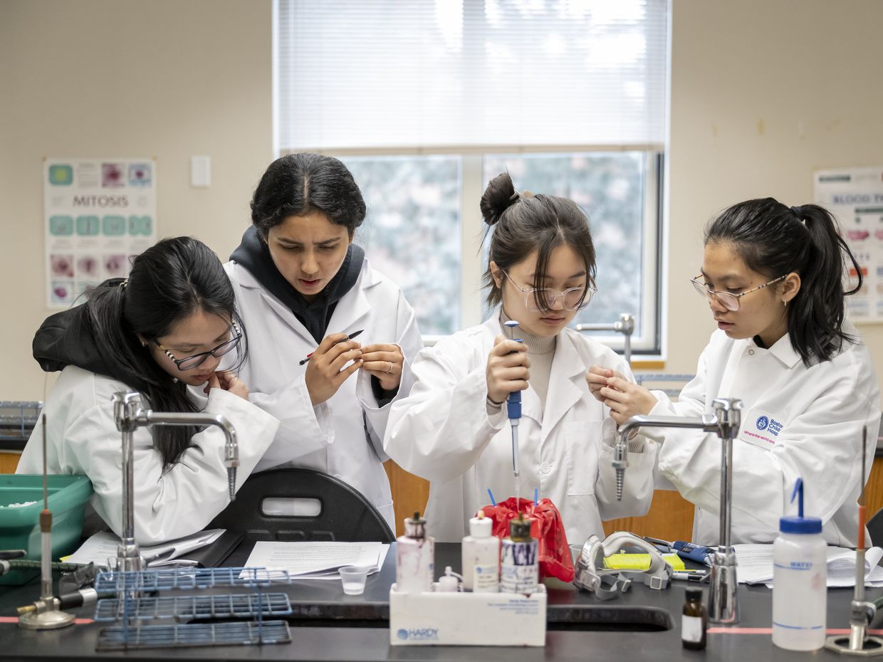 Student's working in big lab classroom, interacting with one another and the professors.