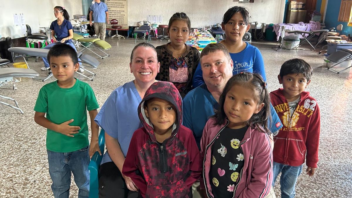 A man and a woman sit with children on a service trip to Guatemala. 