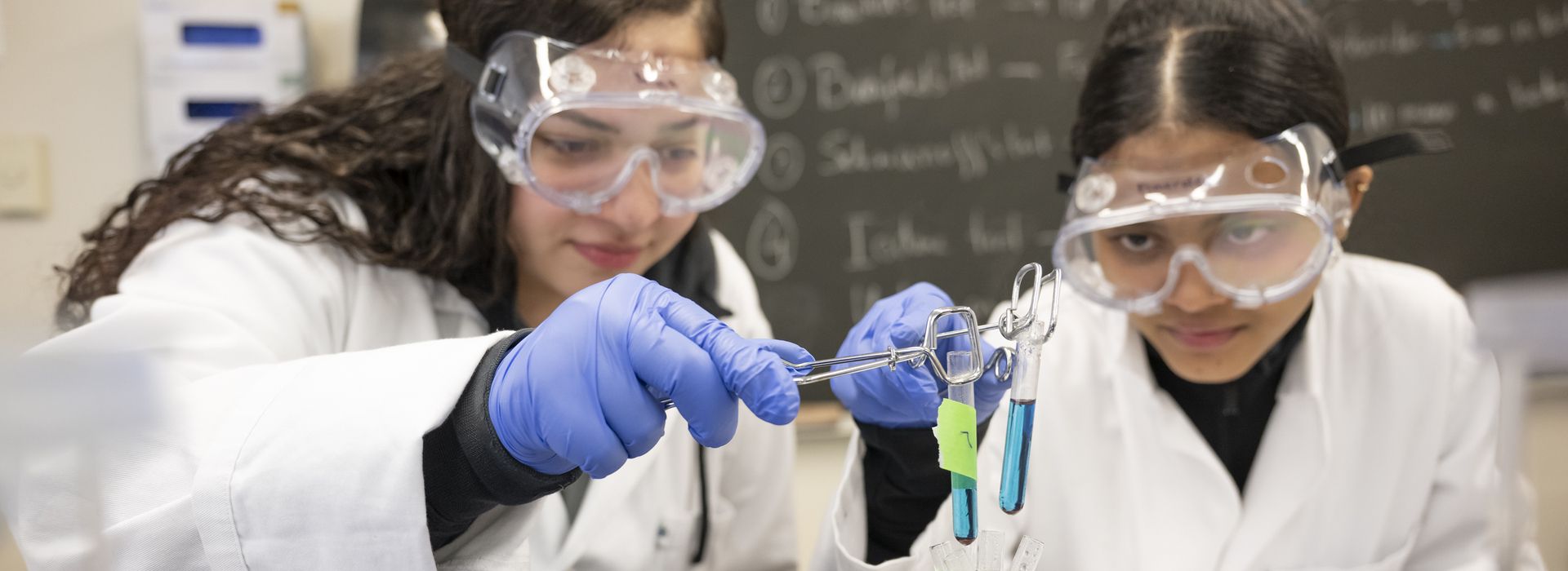 Students working in Boston lab space, professors interacting.Student's working in chemistry lab on the Boston Campus. 