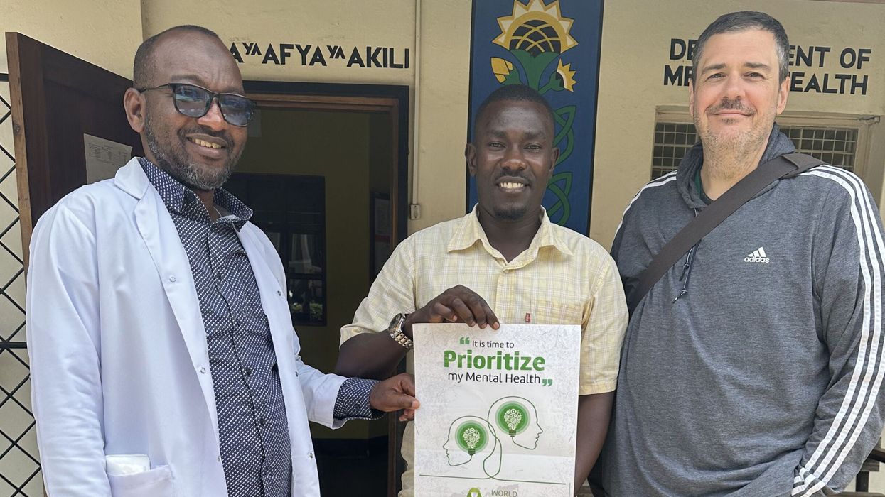 Dr. Trae Stewart stands next to two men in Guinea.