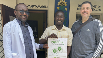 Dr. Trae Stewart stands next to two men in Guinea.