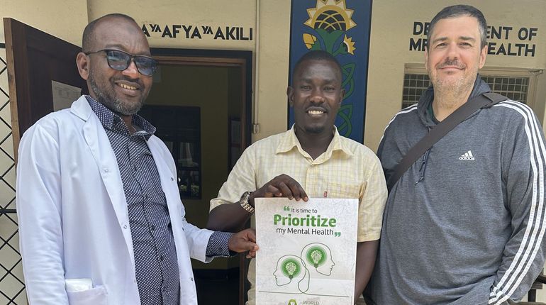 Dr. Trae Stewart stands next to two men in Guinea.