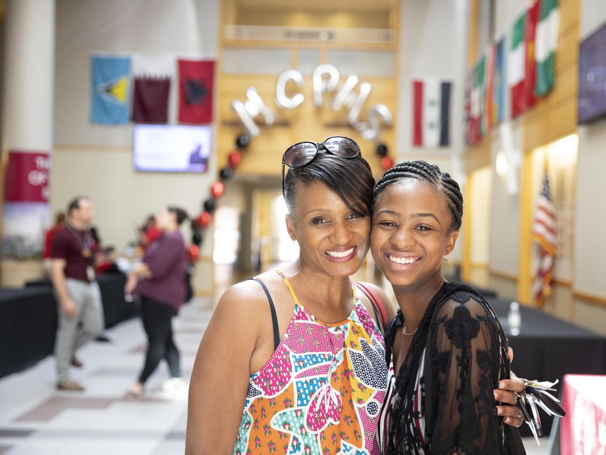 Mother and Daughter smiling and standing in front of balloons that say MCPHS. Orientation