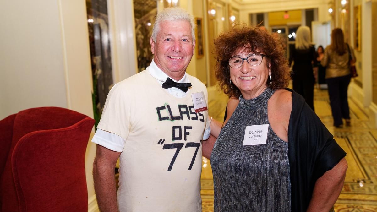 Patrick Contrado wearing a homemade “Class of 77” T-shirt standing with his wife. 